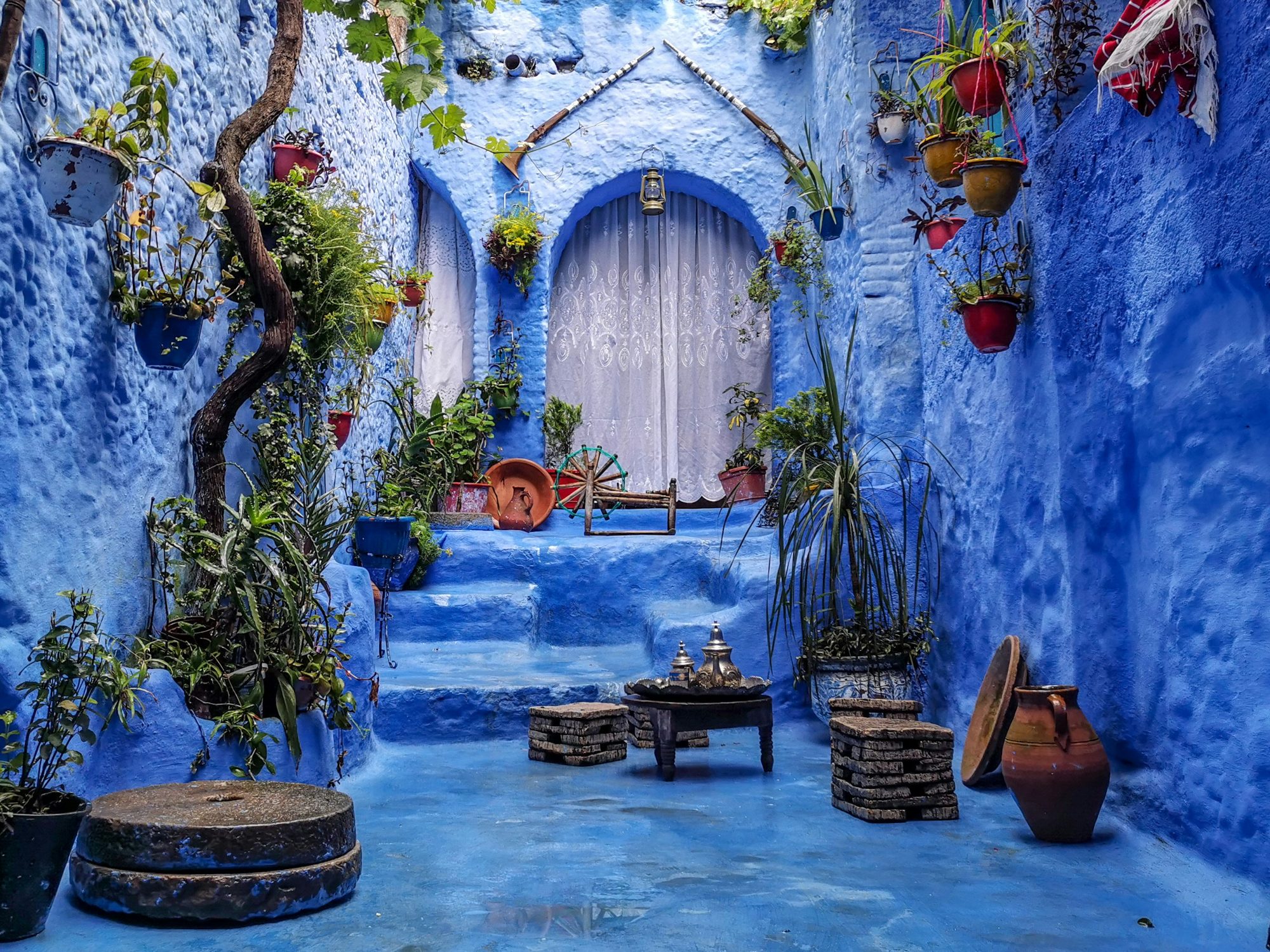Blue-washed courtyard with potted plants and a tea table in Chefchaouen